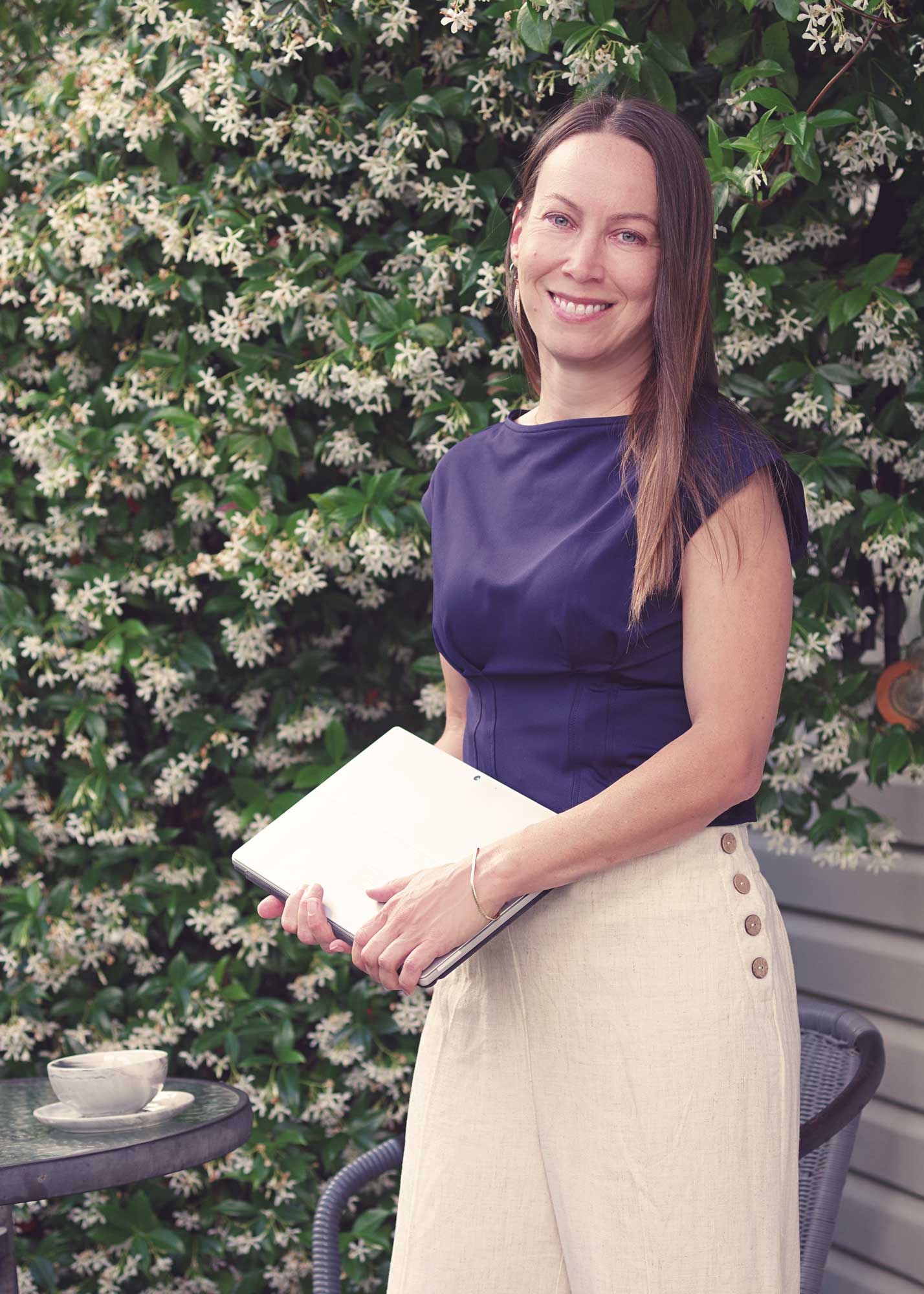 Lynn Hawthorn standing in her garden with her laptop | Physis Publishing | Quietly Iconic Brands